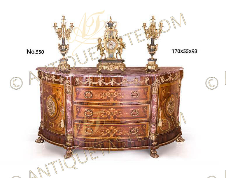 An Empire Napoleonic 19th century style ormolu-mounted, marquetry, veneer inlaid and marble demilune sideboard. The demilune eared marble top above a veneer inlaid shaped frieze ornamented with an exquisite ormolu ribbon-tied torch garlands terminating to each side with a winged Neoclassical style male and female. The shaped frieze above three large drawers and two doors to each side, all are ornamented with foliate marquetry patterns. The section is divided with marble columns supports with gilt ormolu palm capitals surmounted with foliate scalloped ormolu mounts. Bothe drawers and doors are inlaid with ormolu strips all over the contour with a central gilt-ormolu foliate works and urn filled with flower cartouche to each door. The shaped veneer inlaid ormolu striped base ornamented with flower rosettes and raised on a fine chiseled paw feet
